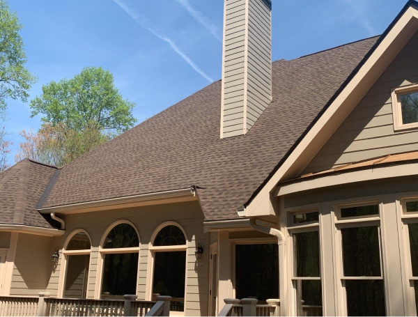 Modern brown shingled roof house with beige siding and decorative columns