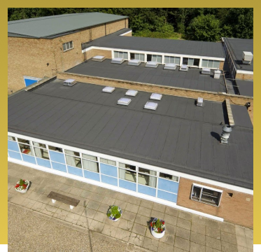 Aerial view of modern school building with flat roof and blue exterior walls