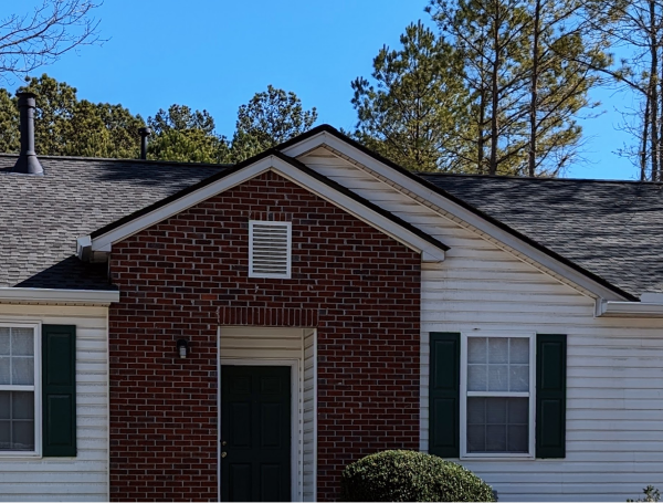 Single-story brick and vinyl siding house with green shutters and front door