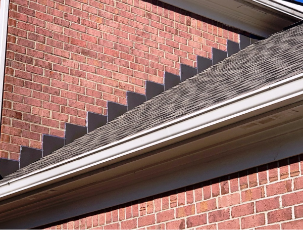 Red brick house exterior with asphalt shingle roof and white gutters