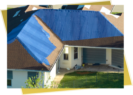 Aerial view of house with blue tarps covering damaged roof sections