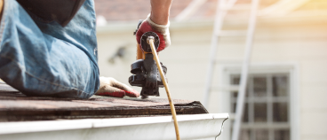 Construction worker using circular saw to cut wood on residential roofing project