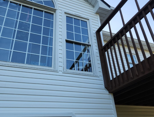White vinyl siding house exterior with large windows and wooden deck railing