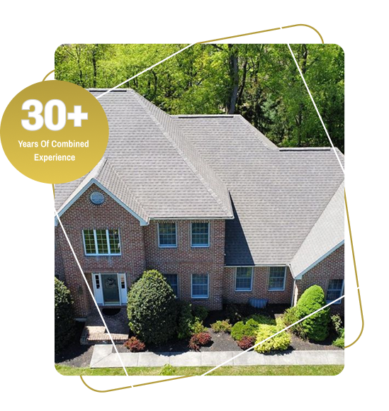 Brick house with gray shingle roof surrounded by landscaped yard and trees