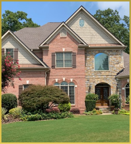 Large two-story brick and stone house with arched entrance and landscaped yard